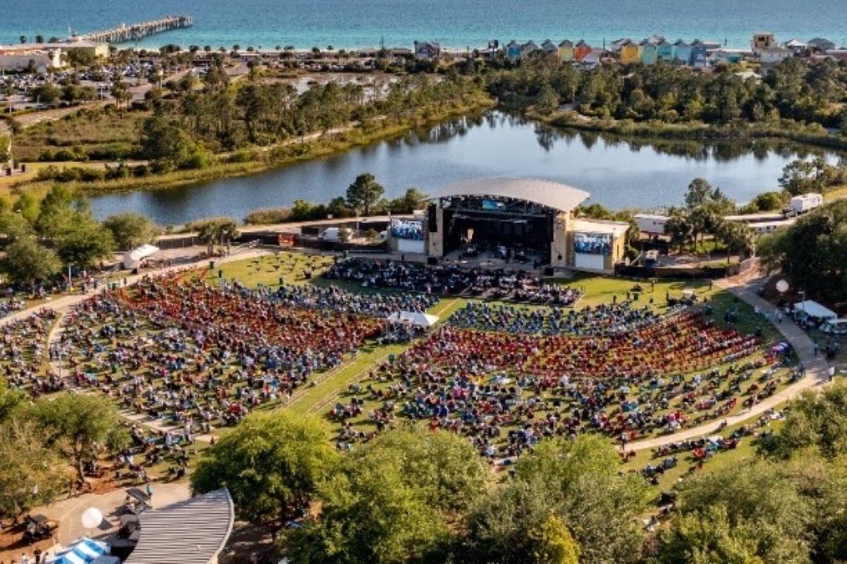 Outdoor amphitheater concert with a large crowd at a coastal destination venue