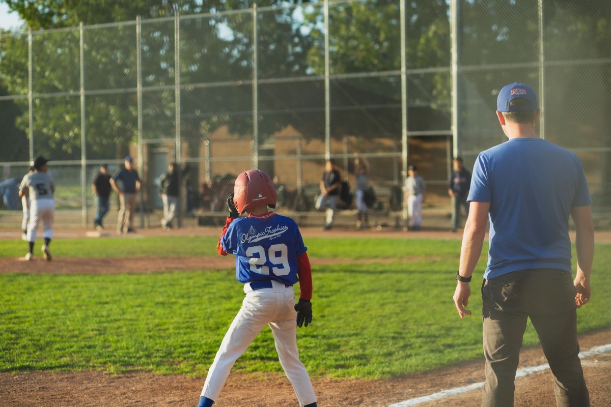 Youth baseball player at bat with spectators watching from behind the fence
